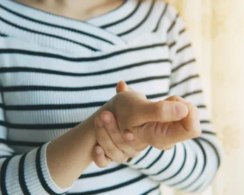 Eine Frau hält ihr schmerzendes Handgelenk.