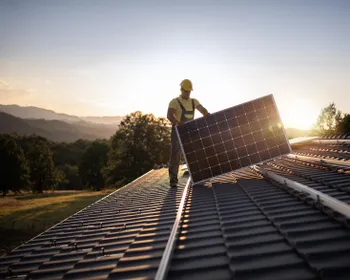 Ein Mensch steht am Dach und montiert ein PV-Panel.