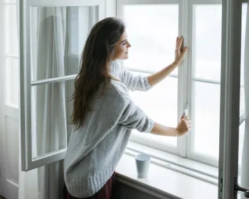 Frau öffnet Fenster zum Lüften.