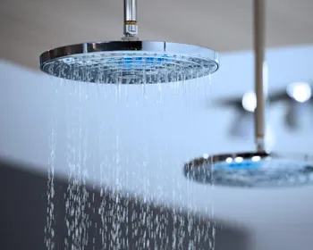 Zwei Duschköpfe sind zu sehen. Aus einem läuft Wasser.