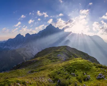 Eine Berglandschaft. Die Sonne scheint durch die Wolken
