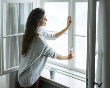 Junge Frau öffnet ein Fenster.