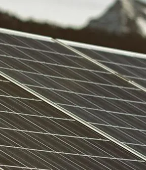 Ein Solarstrom-Park mit zahlreichen PV-Paneelen. Im Hintergrund sind Berge.