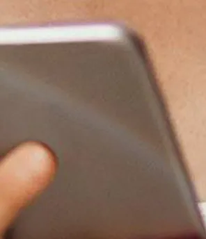 Junge Frau hält ein Smartphone in der Hand und lächelt dabei während sie sich für den VERBUND-Newsletter anmeldet.