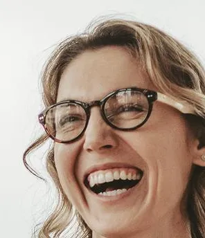 Zwei Frauen stehen sich an einem Meetingtisch gegenüber, freuen sich und schlagen die Hände ein.