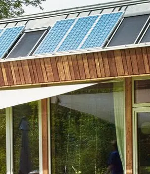 Modernes Holzhaus mit einer PV Anlage am Dach mitten im Grünen.