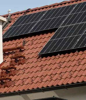 Haus mit rotem Dach und PV-Paneelen.