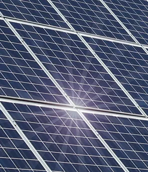 Eine Photovoltaikanlage auf einem roten Hausdach. Es scheint die Sonne und sie spiegelt sich darauf