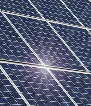 Solarpaneele auf einem roten Hausdach. Es scheint die Sonne und sie spiegelt sich auf den Paneelen.