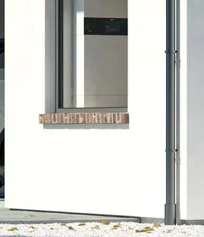 Ein weißes Einfamilienhaus mit grauen Dach. Am Dach ist eine PV-Anlage, in der Garage steht ein E-Auto und vor dem Haus ist die Außeneinheit einer Wärmepumpe.
