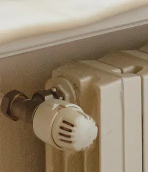Ein weißer Heizkörper unter einer Fensterbank, auf der eine weiche Decke liegt