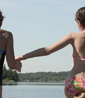 Zwei Frauen im Badeanzug springen in einen See.