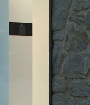 Ein modernes Einfamilienhaus. Davor steht das Außengerät einer Wärmepumpe.
