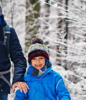 Eine Familie in Winterkleidung läuft im verschneiten Wald