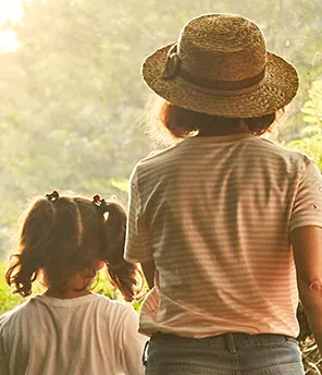 Man sieht von hinten drei Kinder, die im Wald spazierengehen.
