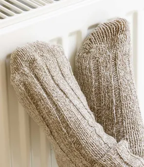 Füße mit dicken Wollsocken, die an Heizkörper lehnen
